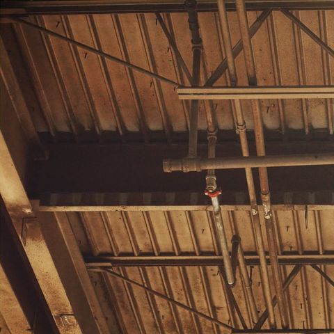 Plant ceiling before cleaning: dust and grime on the deck, trusses, pipe and conduit