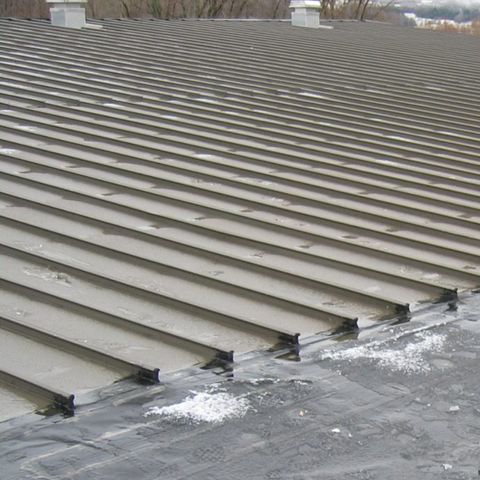 A metal roof before coating: weathered, rusting at the seams and fasteners